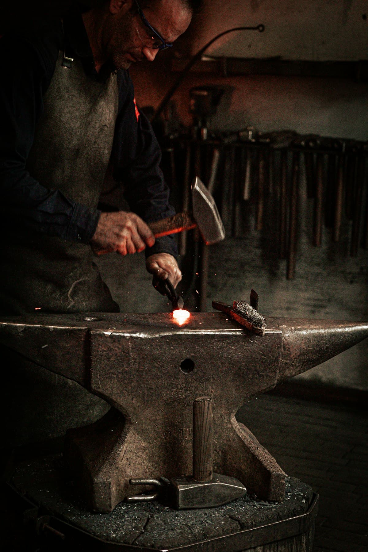 Blacksmith forging glowing steel on an anvil, the craft behind Drop Forge Creative